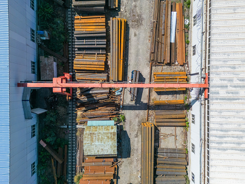Aerial top down view of workers loading stack of metal pipes with gantry crane