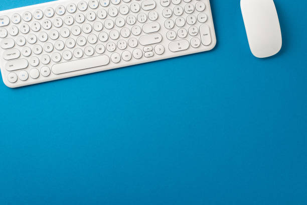 istock Modern Office Essentials: Top view composition with white keyboard, and wireless mouse on blue surface. Blank space for text or ads 1657232276