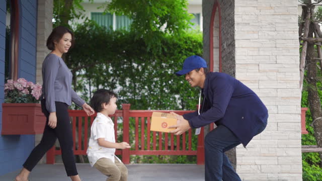 Messenger Delivery man send a package box to little boy and mother customer with happy emotion at there home.