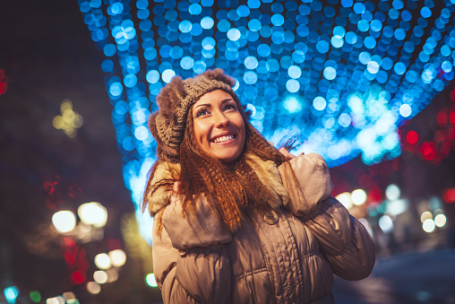 Cheerful young woman is having fun in the city street at Christmas time.