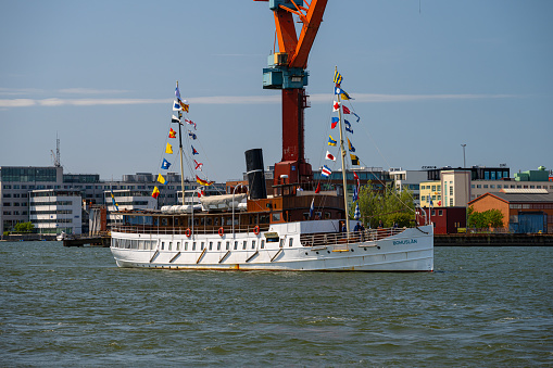 Gothenburg, Sweden - June 03 2023: Old tourist ship Bohuslän with testive signal flags steaming up the river.