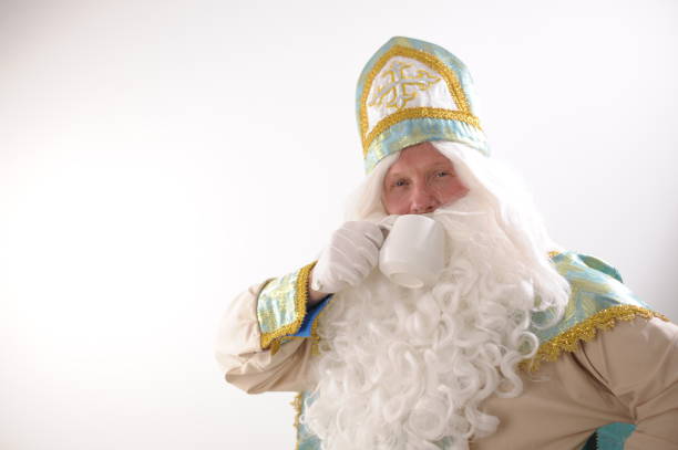 istock place for text on a white background a man in a costume of St. Nicholas drinks tea from a white cup Sinterklaas portrait. USA on a white background. Dutch Santa Claus St Nicholas christmas new year 1657362087