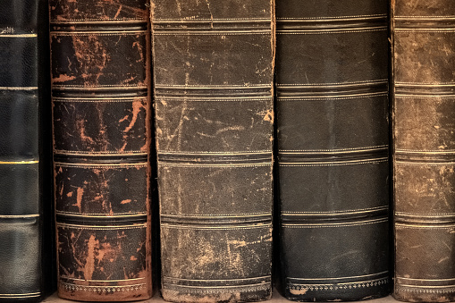 Ancient old books on shelf in the library. Tiled Bookshelf background