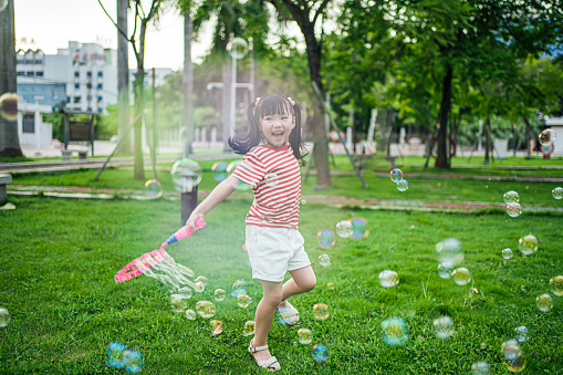 Girls playing with soap bubbles in outdoor parks，A cute Asian girl