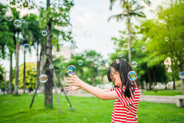 Girls playing with soap bubbles in outdoor parks，A cute Asian girl
