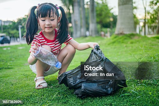 istock The girl picked up the beverage bottle on the ground and put it into the garbage bag，Environmental protection theme, caring for nature theme 1657362604