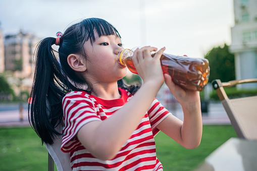 An Asian girl drinking a drink in the park