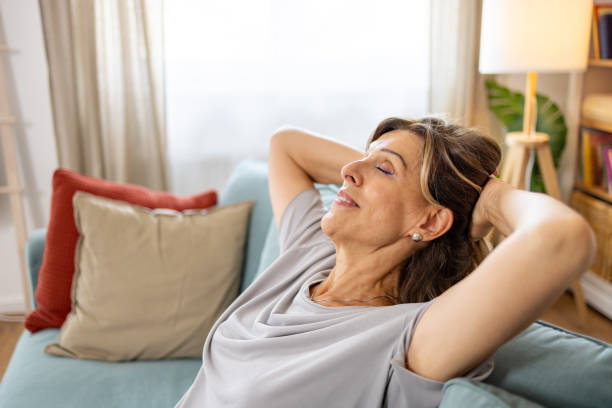 istock Woman with hands behind head relaxing on cozy couch 1657389038