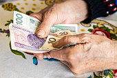 Polish old woman pensioner clutches money in her hands, small amount, Concept, Difficult financial situation of elderly people in Poland, Rising fees and food prices, close up