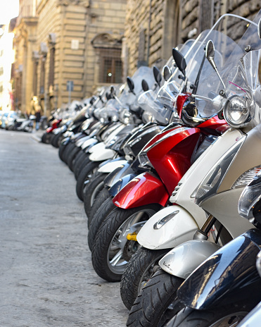 Florence, Italy - 22 Nov, 2022: Classic Italian Vespa scooters parked in line on a street in Florence