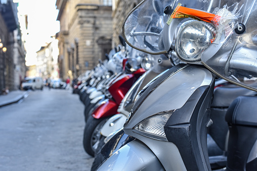 Florence, Italy - 22 Nov, 2022: Classic Italian Vespa scooters parked in line on a street in Florence