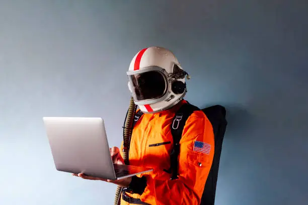 Astronaut in spacesuit works on laptop, High-tech space exploration concept