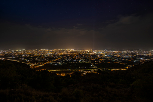 Panoramic view of the city and orchard of Murcia illuminated at night, from El Valle Natural Park