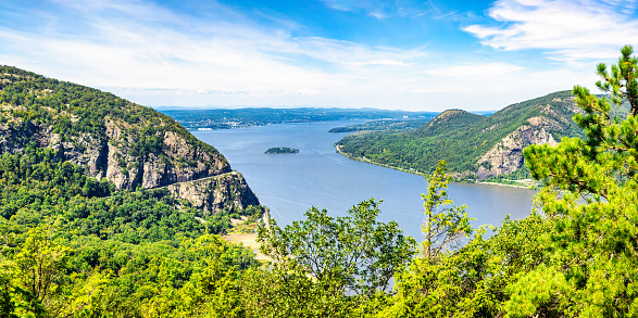 Panoramic view of Hudson river with Storm King highway around Storm King Mountain cliffs, Bannerman Island in the middle and Sugarloaf mountain on the right.