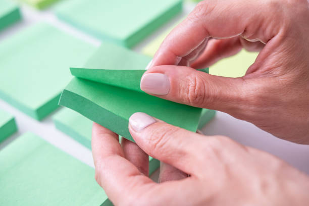 istock Close up of hands peeling off a green sticky note. 1657471221