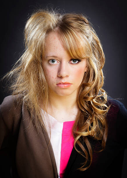Closeup portrait of beautiful young blond woman with long hair, light blue background.