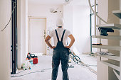 Unrecognizable Construction Worker Standing with his Arms on Hips, Overlooking the Apartment He is Renovating