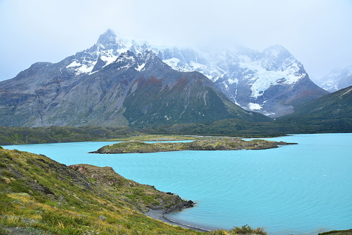Towering mountains rise behind blue waters in Torres del Paine National Park.