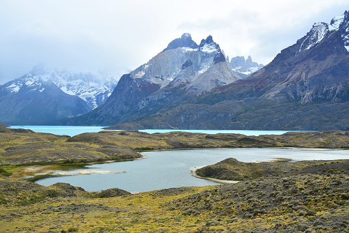 Towering mountains rise behind blue waters in Torres del Paine National Park.