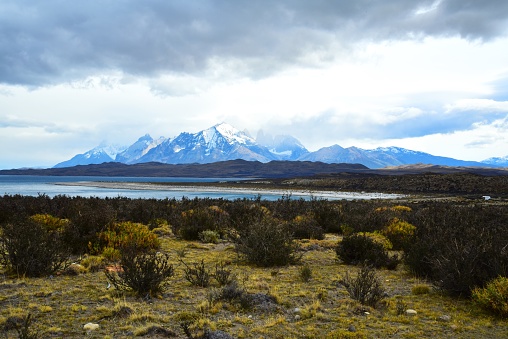 Mountains in Torres del Paine National Park rise behind a lake in the landscape of Patagonia, Chile.