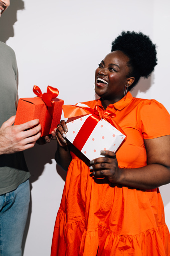 An anonymous Caucasian man giving a birthday gift to a happy black woman.