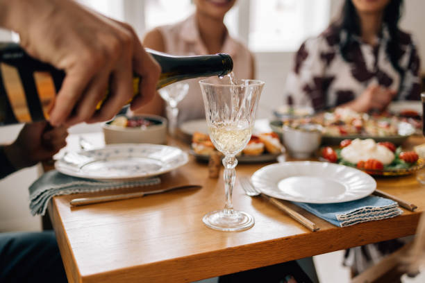 istock Anonymous Man Pouring a Drink into a Fine Glass while Having Lunch with Friends 1657592230