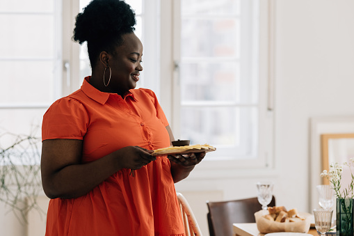 A smiling African American overweight woman setting the table for a lunch party.