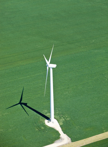 A large industrial wind turbine towers above a summer soybean field. The distinct shadow could be used alone to demonstrate a living in the shadow of a wind turbine concept. With the debate over proximity of turbines to homes you could use the shadow with the turbine or as an outline for your own illustration. http://www.banksphotos.com/LightboxBanners/Aerial.jpg http://www.banksphotos.com/LightboxBanners/WindEnergy.jpg