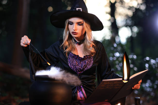 The fantasy woman witch conjures, holds a magic wand and a magic book in her hands, and reads spell white magic smoke from boiling vat. Halloween theme. Witch performs ceremony on Halloween day The fantasy woman witch conjures, holds a magic wand and a magic book in her hands, and reads spell white magic smoke from boiling vat. Halloween theme. Witch performs ceremony on Halloween day halloween pumpkin human face candlelight stock pictures, royalty-free photos & images