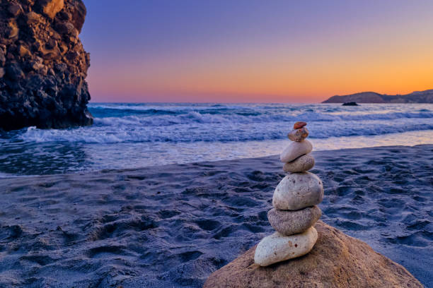 해질녘 모래 해변에 있는 돌 더미와 큰 자연 바위의 균형을 맞춥니다. - cairn stacking stone rock 뉴스 사진 이미지