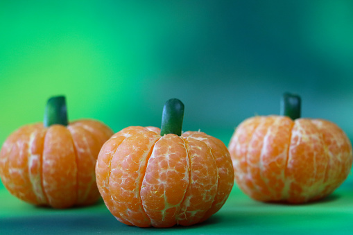 Stock photo showing close-up view of Halloween party themed food ideas. This picture is of a group of 'pumpkins' made from satsumas with stalks made from pieces of cucumber.