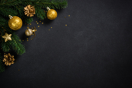 Black christmas background with fir tree and holiday decorations. Flat lay image with space for design.