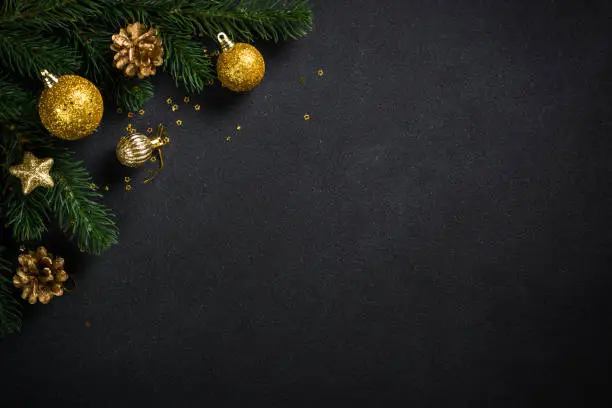 Photo of Black christmas background with fir tree and holiday decorations.