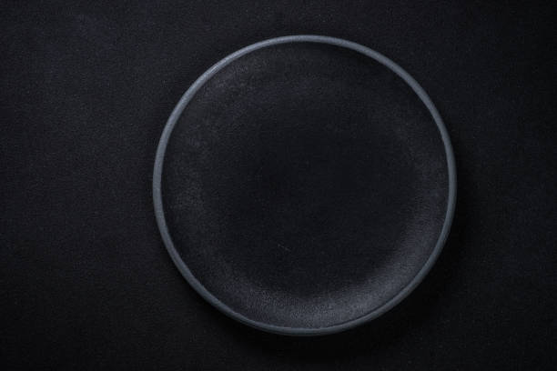 istock Black plate at black background. Top view. 1657628129