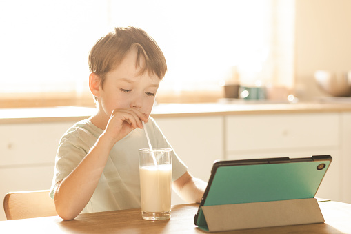 6 year old boy drinking milkshake in home kitchen