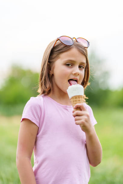 istock Little girl eating an ice cream cone holding it with both hands 1657639900