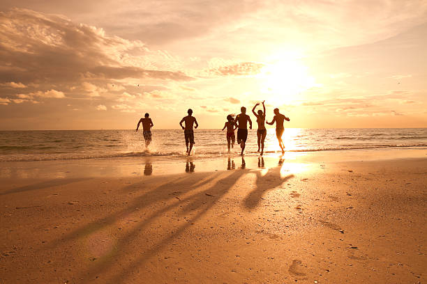 grupo de amigos divirtiéndose en la playa - focus on shadow shadow women silhouette fotografías e imágenes de stock