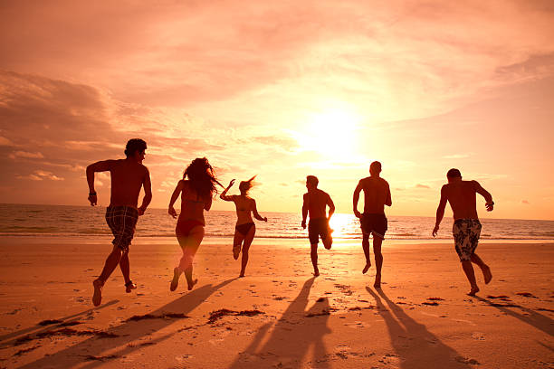 istock Group of friends running on the beach at sunset 165764954