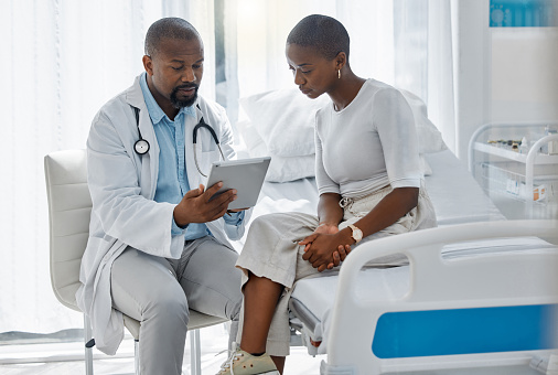 Doctor consulting patient with digital tablet, giving diagnosis and medical checkup in a hospital. Healthcare worker and trusted physician in appointment with medicine advice, wellness and feedback
