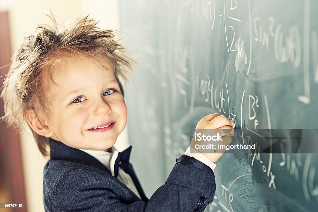 Little Scientist Cute little boy with messy hair solving difficult equations. E=mc2 Stock Photo