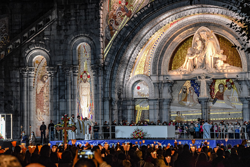 Lourdes, France - 9 Oct 2021: Pilgrims attend the Marian Torchlight Procession service at the Rosary Basilica in Lourdes