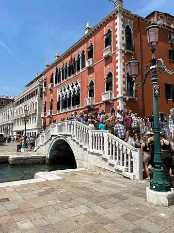 Riva degli Schiavoni, Venice, Italy - July 12, 2023: Stock photo showing close-up view of the Ponte della Vin spanning Rio del Vin with crowds of tourists crossing the canal, on a sunny Summer's day.