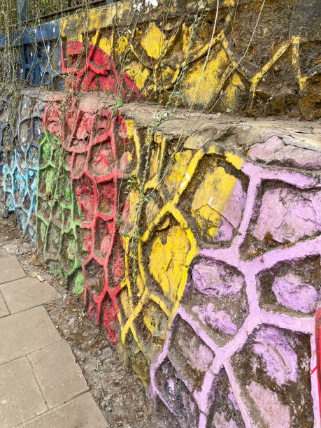 istock Close-up image of multicoloured painted, textured pattern public park wall, blue, yellow, pink, green and red, paving stone pavement, Mumbai, India, focus on foreground 1657692028