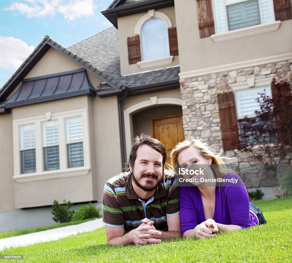 Happy Couple Happy Caucasian couple smiling in front of a house.   Adult Stock Photo