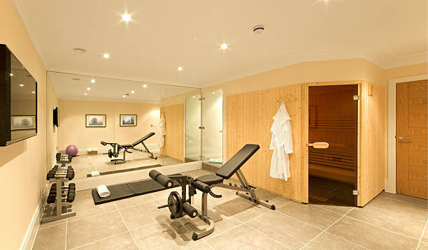 domestic gym a gym in the basement of an exclusive new home, fitted with exercise equipment including weights, a bench, ball and floor mat. A pine-panelled sauna and shower room are also part of the complex. Trimmings include towels and a dressing gown.  exercise room stock pictures, royalty-free photos & images