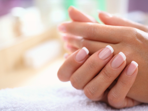 Closeup of fine manicured fingernails on female hands,carefully retouched at 200%. Standard french manicure with transparent nail polish. Hands are placed on white towel.