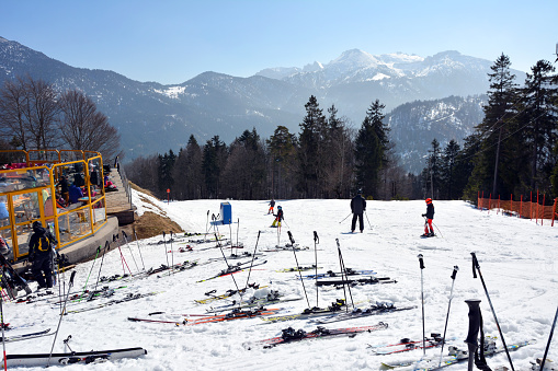A man and several children of unrecognizable appearance are going down a ski slope on skis together. Family vacation in winter against the background of beautiful mountains