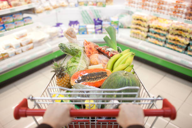 A person pushing a cart full of fruit at the store stock photo