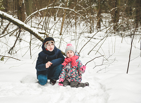 sister and brother walk in the winter forest