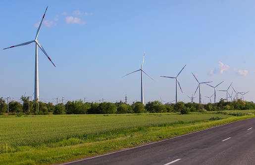 Wind power generators along a suburban highway against the sky